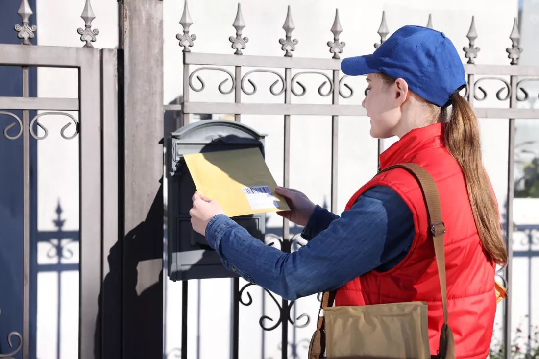 postwoman-putting-envelope-into-mail-box-outdoors